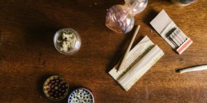 flat lay of cannabis, matches, pipe and grinder