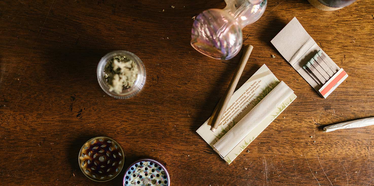flat lay of cannabis, matches, pipe and grinder